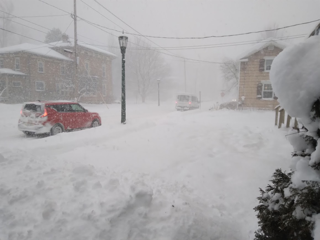 Car driving on a snow-covered street in Northern New York during a snowstorm