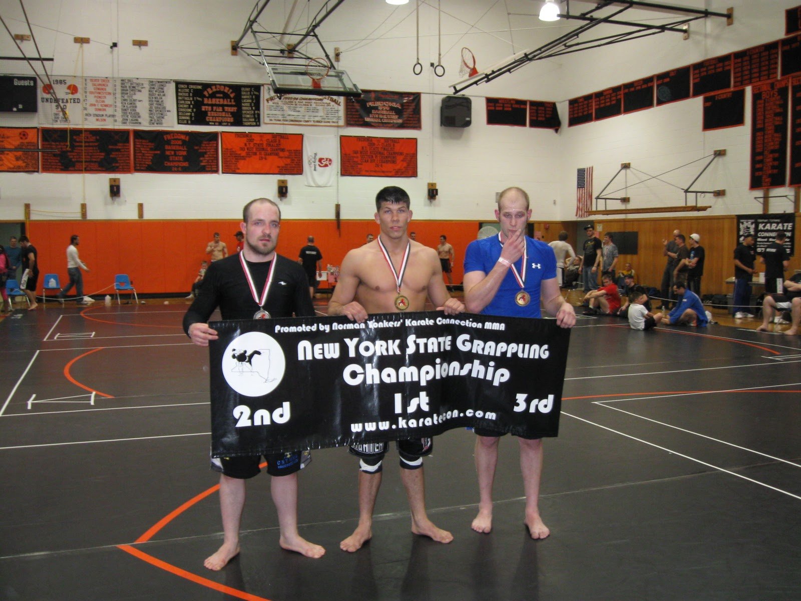 Dustin Baker at center on the first-place step of the podium at the 2009 New York State Grappling Championship in Fredonia, holding the championship banner with two other medalists