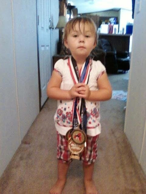Savannah Baker, age two, wearing her father's grappling medals