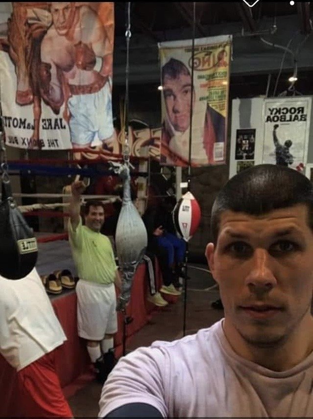 Dustin Baker inside the Watertown Area Boxing Club, with the ring and a Rocky poster behind him